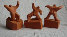 A group of 3 male figures assume energetic postures. Terra cotta height 12cm overall.