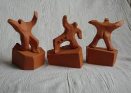 A group of 3 male figures assume energetic postures. Terra cotta height 12cm overall.
