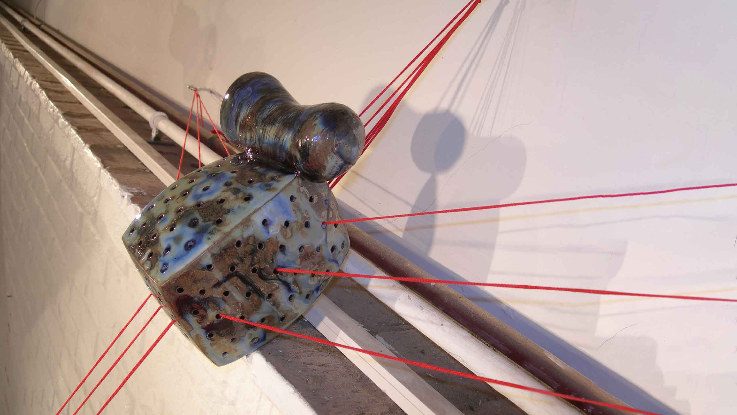 Photo of 'On the threshold of destiny' a ceramic installation of six ceramic compositions linked together with three strands of bright red cord.