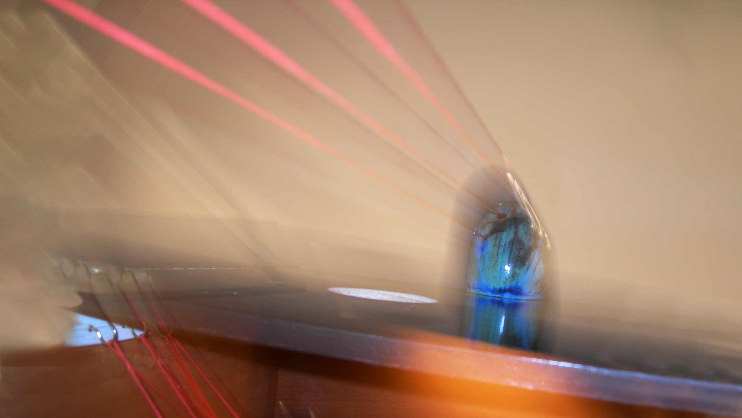 Blurred photo of one of the compositions in 'On the threshold of destiny' a ceramic installation comprised of six ceramic objects linked together with three strands of bright red cord.