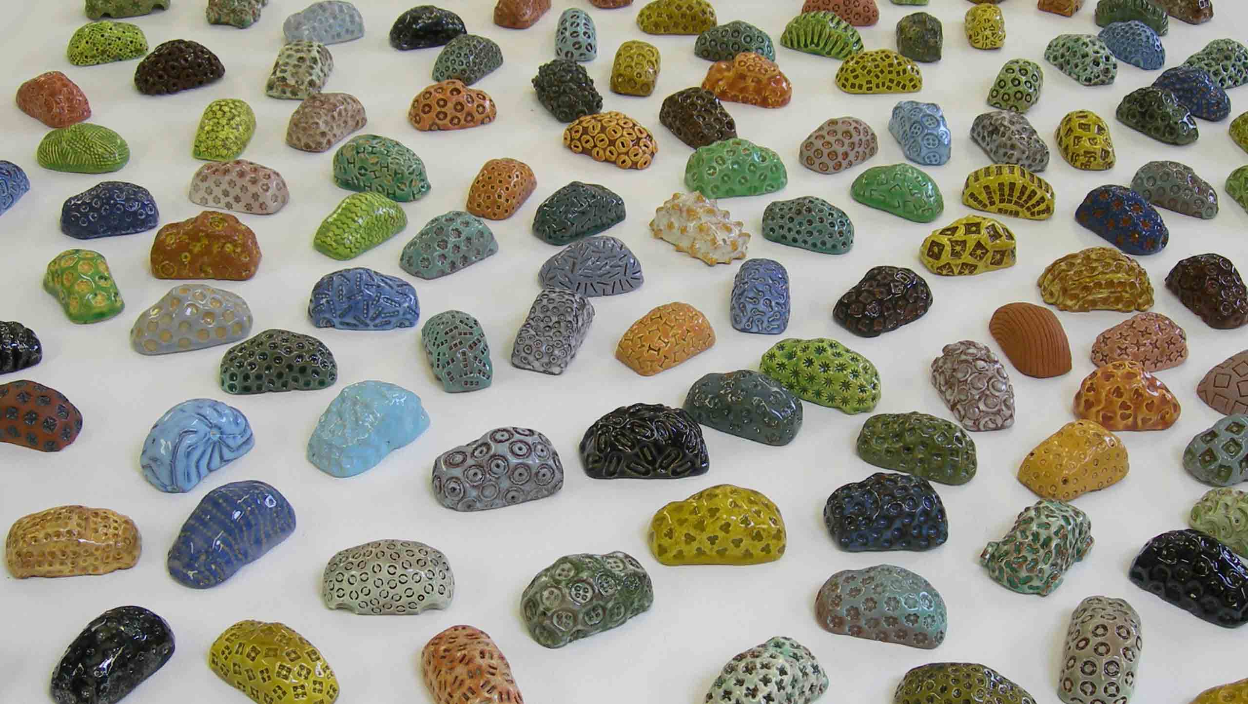 Karparc: A large group of loosely modelled glazed car forms. A crowd of randomly parked 'cars' fill the view. They are in many different colours and impressed with different shaped implements.