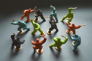 Riot of colour. A set of twelve brightly coloured figures in fighting stances wielding wooden clubs by ceramic sculptor Simon Fell
