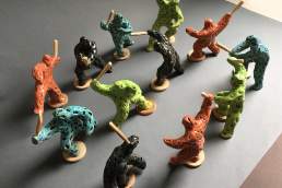 Riot of Colour - twelve small coloured figures with clubs, figures about 10cm tall