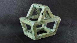 Unexpected Item - An object in the shape of a supermarket shopping basket made with extruded square section tubes of earthenware clay, fired and glazed with a reflective copper glaze