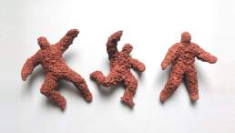 Falling Figures, unglazed terracotta figures about 10cm in length encrusted with embossed forms